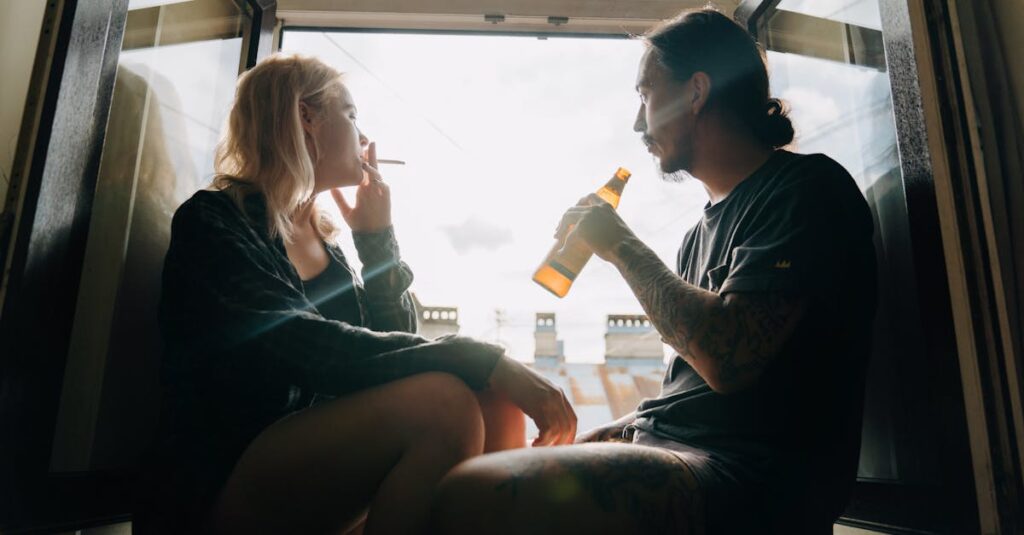 pexels-photo-5097401-5097401 A couple sits by an open window enjoying a beer and cigarette, sharing a quiet moment together.
