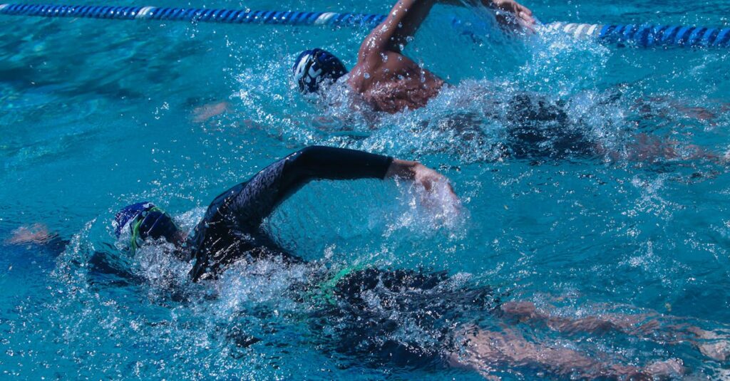 pexels-photo-11953714-11953714 Two swimmers competing in an outdoor pool, showcasing speed and skill.