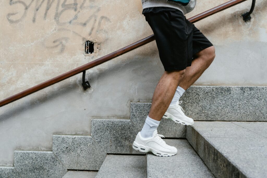 Adult male in athletic attire climbing stairs outdoors, emphasizing fitness and energy.